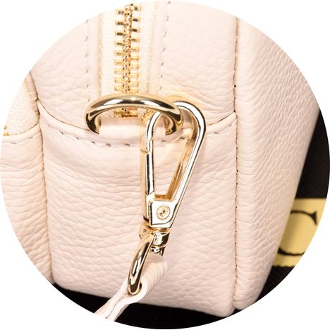 close up of a chunky gold metal strap clip on a womens cream small handbag