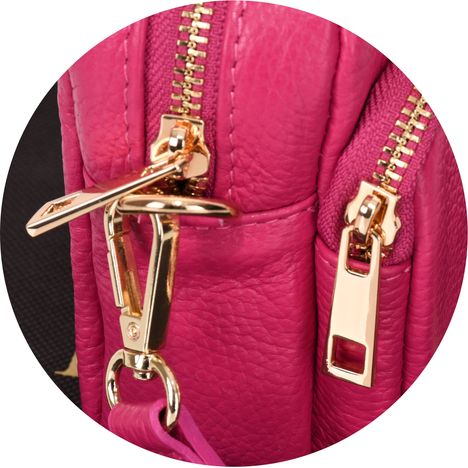 close up of a chunky gold metal zip pullers on a womens pink small crossbody handbag