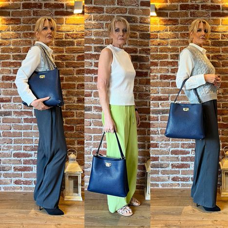 dark blue italian leather large tote bag modelled on the shoulder being held and worn on the arm 