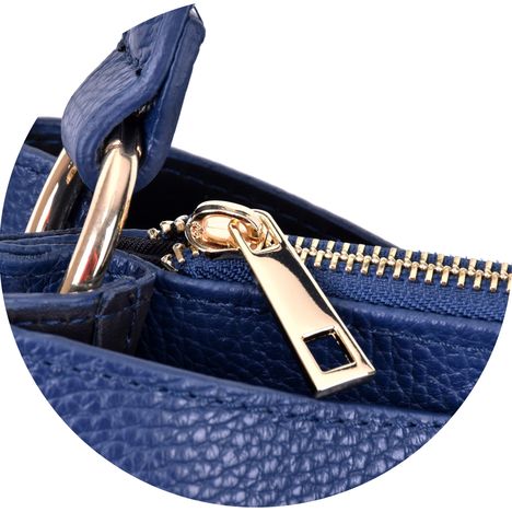 close up of the chunky gold metal zip puller on a womens dark blue italian leather handbag