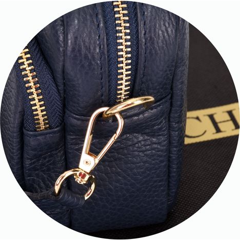 close up of a chunky gold metal strap clip on a womens navy blue small crossbody handbag