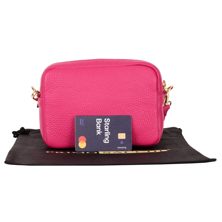 rear of womens small pink leather shoulder & crossbody bag with a debit card for size guidance