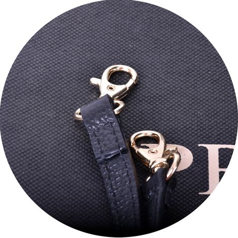 close up of the gold metal clip on a shoulder strap for a womens large black leather grab bag
